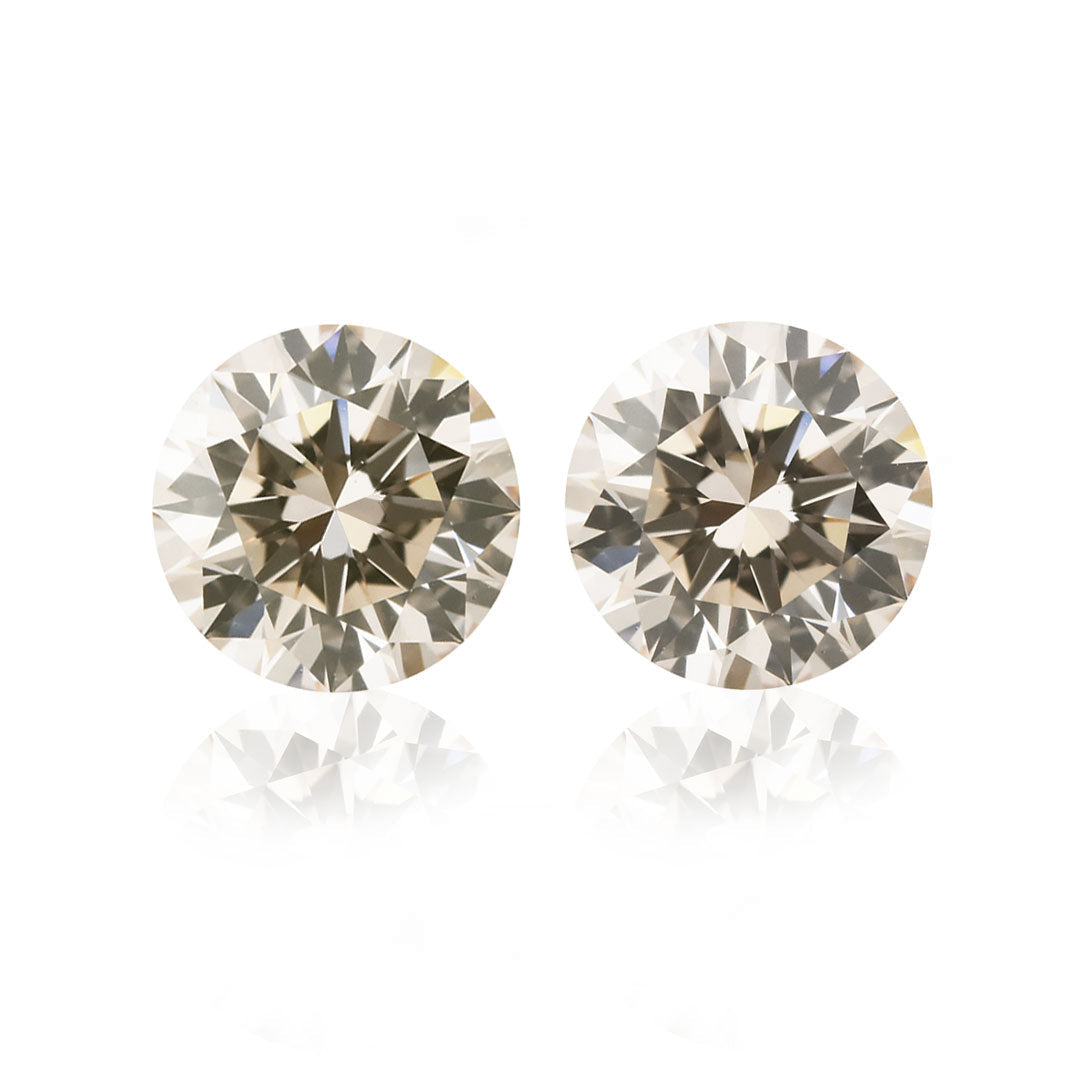 A matched pair of round brilliant cut light champagne colored diamonds.