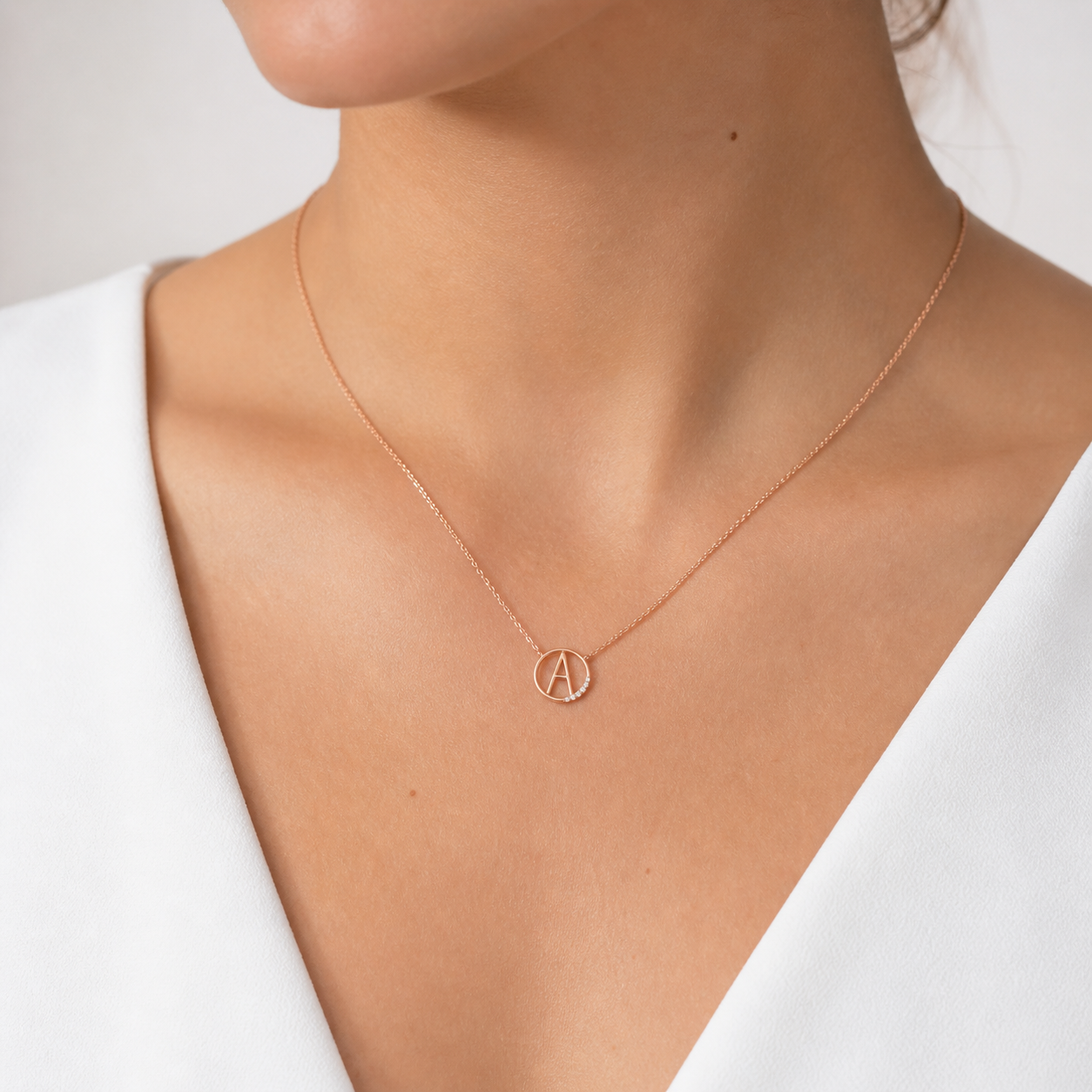 Rose gold necklace with Argyle white diamonds with a circular pendant on a person wearing a white top.