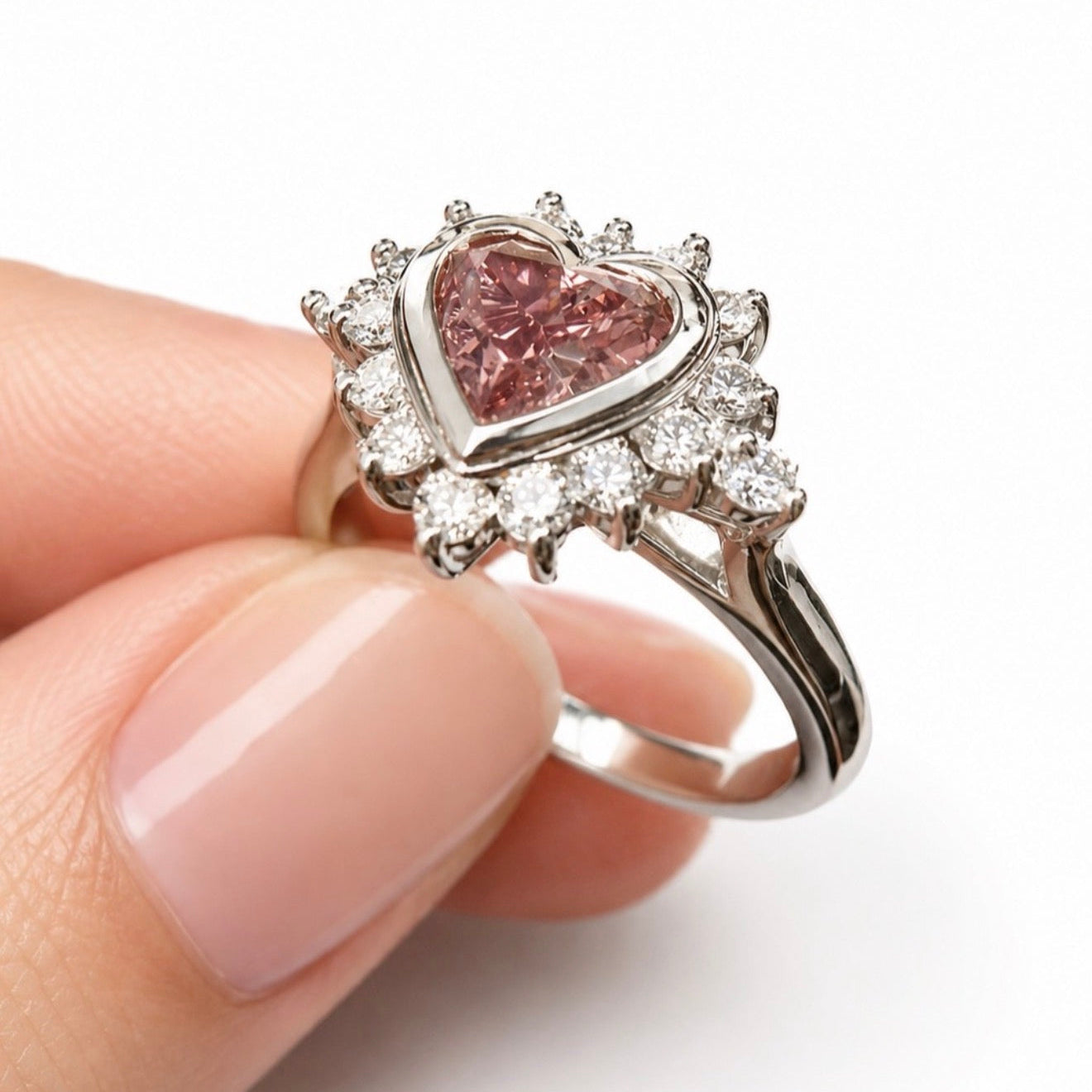 Heart-shaped Argyle pink diamond ring held by a hand on a white background