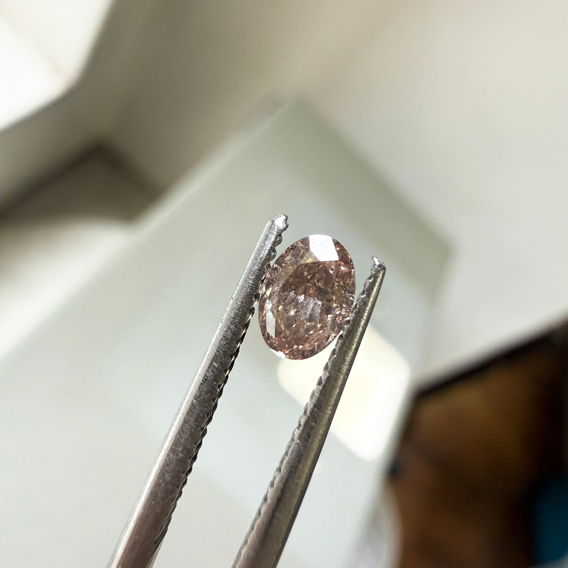 Diamond held between tweezers with a blurred background