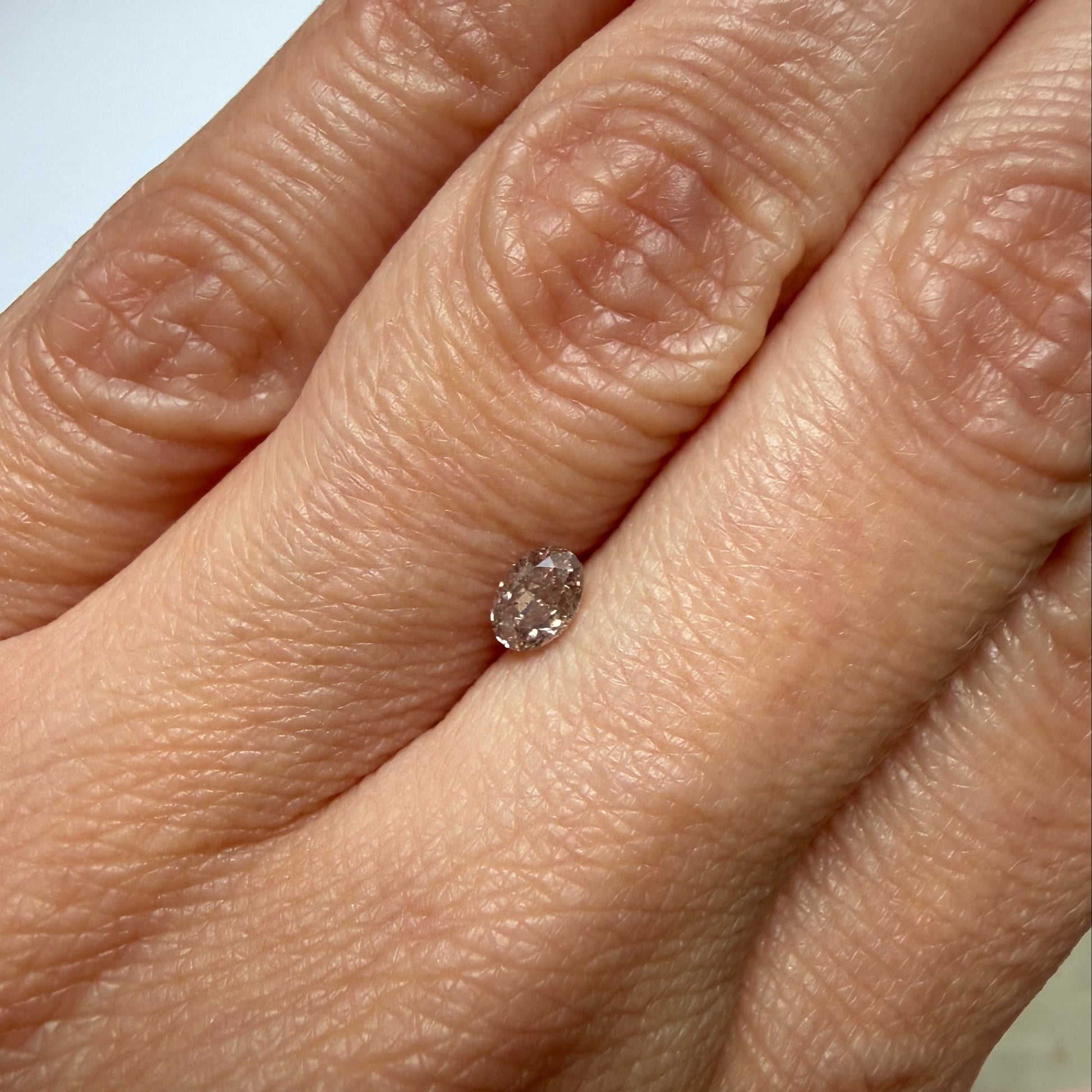 Close-up of a hand wearing a diamond ring on a neutral background